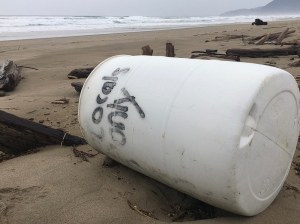 White plastic barrel with locals only written on it; beach and surf in the background
